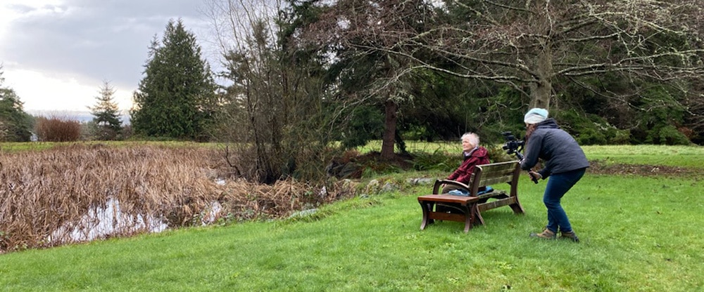 A videographer films the subject of a nonprofit video in an outdoor setting.