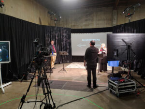 Two auctioneers and a show director prepare to livestream an auction from the studio