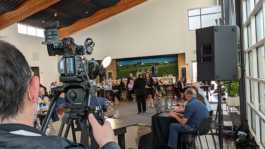 A camera is positioned in a back corner of the room during a hybrid event to show the in-person audience.