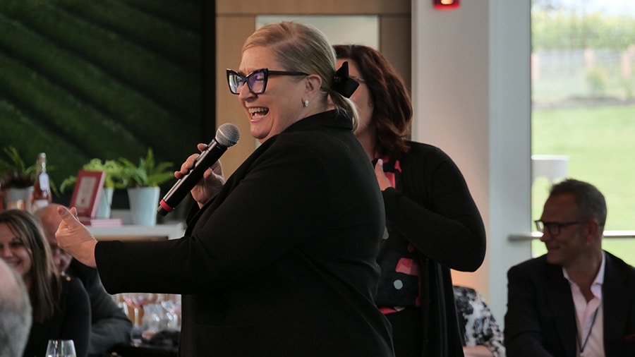 An auctioneeer calls out online bids and in-room bids for an benefit auction during a hybrid event