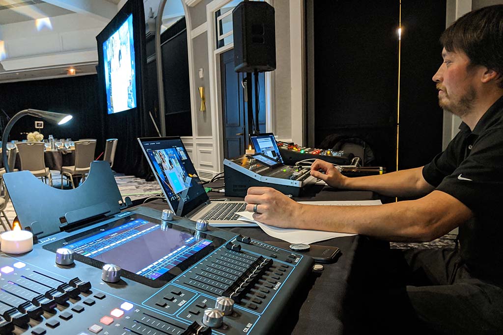 AV technician at the tech table for a live event in a hotel ballroom
