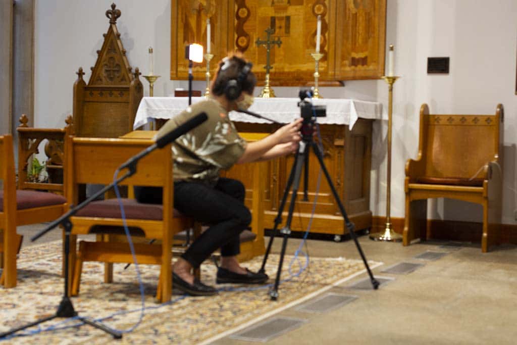 a videographer wearing headphones is filming in a chapel
