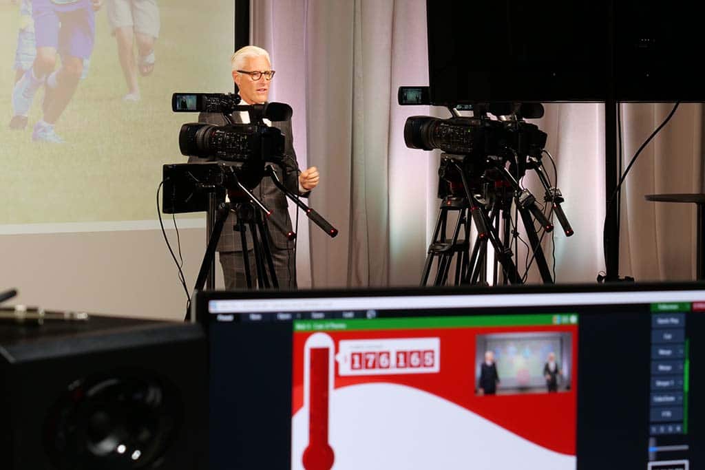 a fundraising host speaks toward two cameras during a livestream virtual event