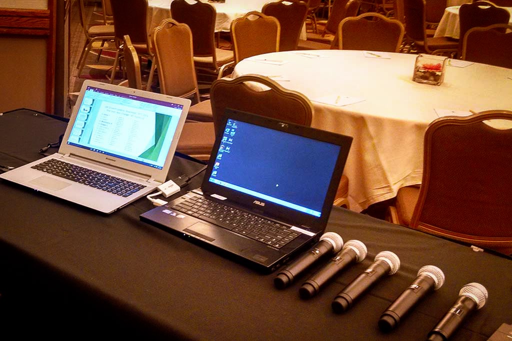 AV rental equipment including laptops and microphones set up in a hotel ballroom for a conference