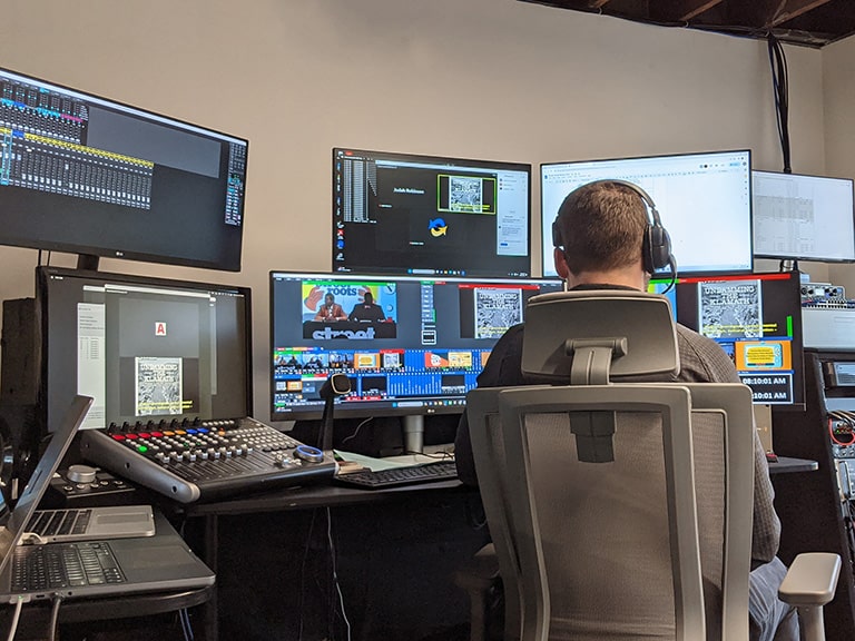 A production engineer live streams a virtual event working with multiple computers and streaming equipment